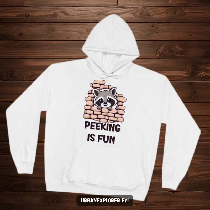 Funny hoodie featuring a cheerful raccoon peeking from behind a crumbling brick wall, a cozy and humorous apparel choice.