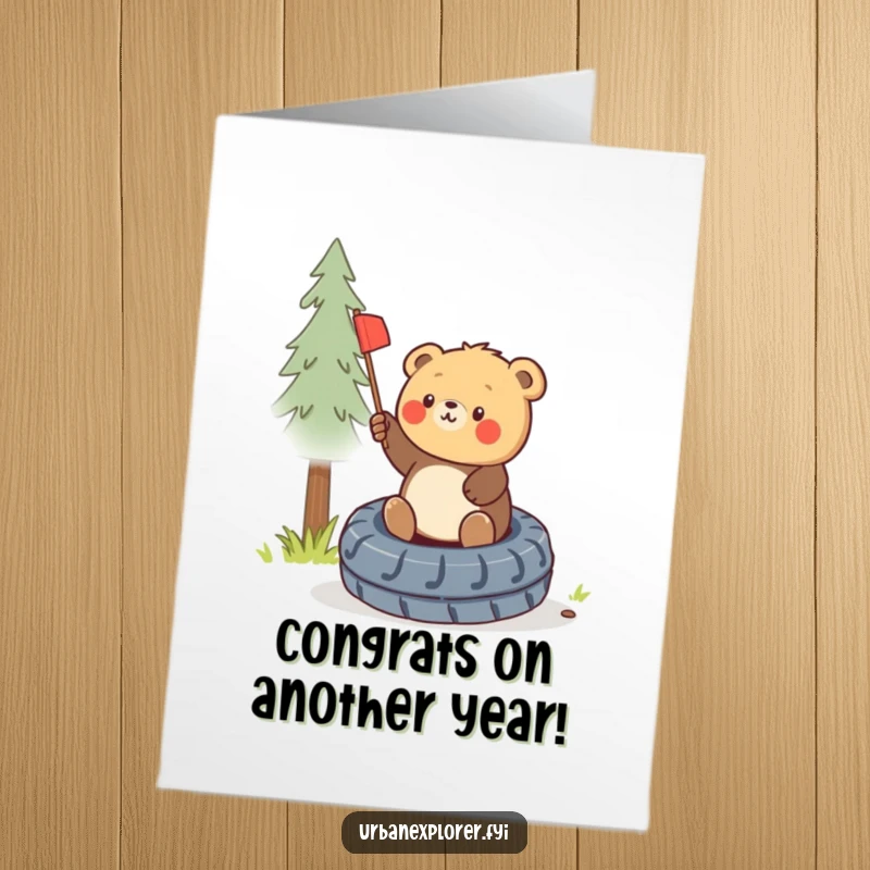 Funny Free Printable Birthday Card: Round bear cub triumphantly planting a miniature flag on a tire.