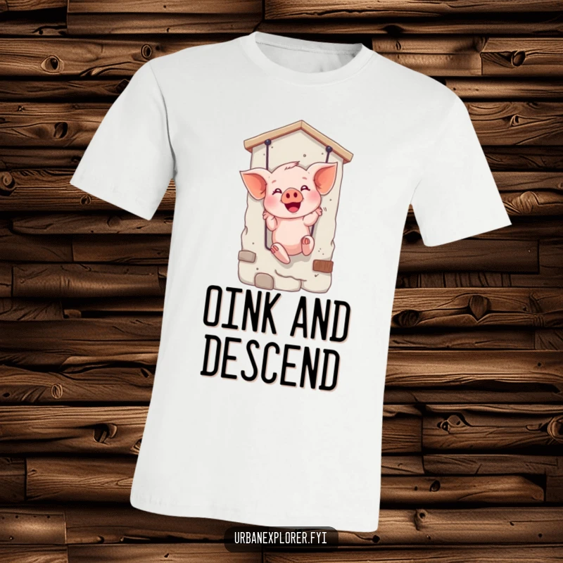 Funny t-shirt featuring a giggling piglet bravely rappelling down a textured wall, radiating excitement and fun.